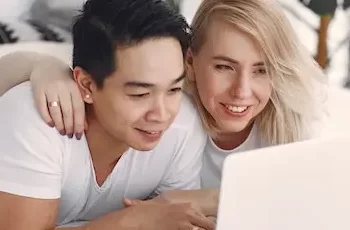 casal na cama assistindo séries e filmes pelo nottebook