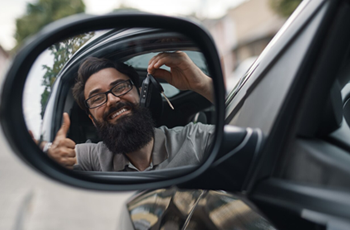 Homem no retrovisor de um carro com chave